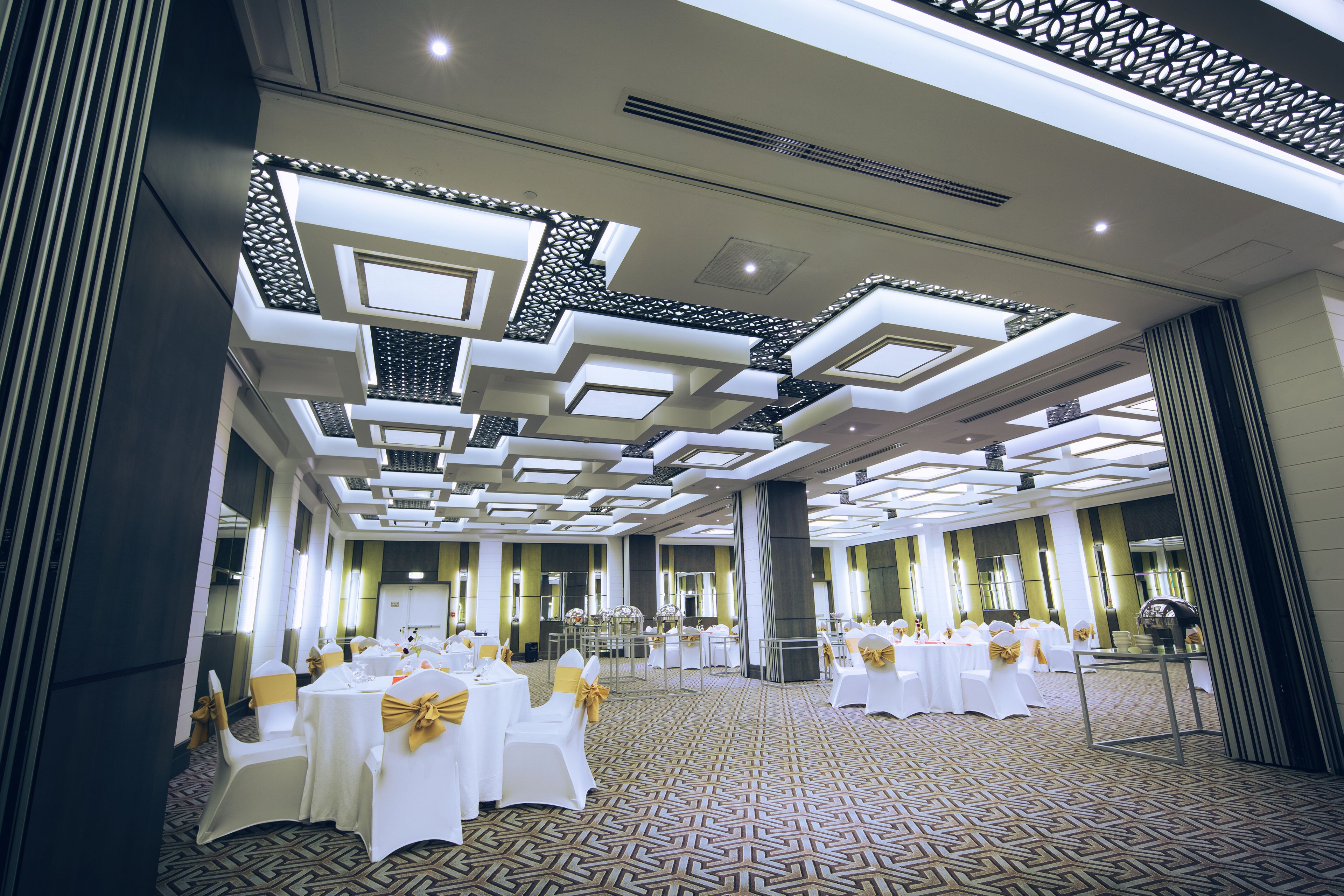 A spacious banquet hall with high ceilings, patterned flooring, and tables set for events.