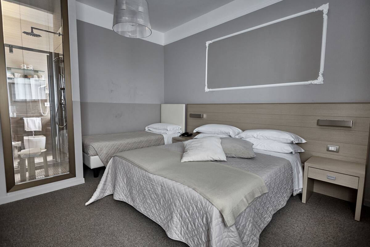 Une chambre moderne avec deux lits, un espace douche et une grande fenêtre.