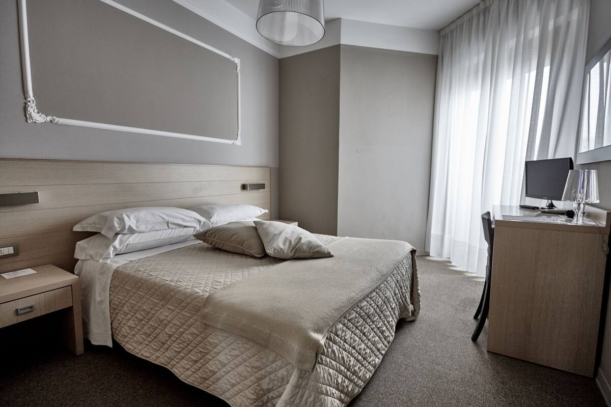 Une chambre d’hôtel moderne, dotée d’un grand lit, d’un bureau et d’une chaise.