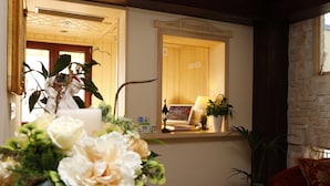 A reception area with a wooden reception desk, a reception sign, and a mirror reflecting the interior. - Hotel Villa Clementina (Scafati)