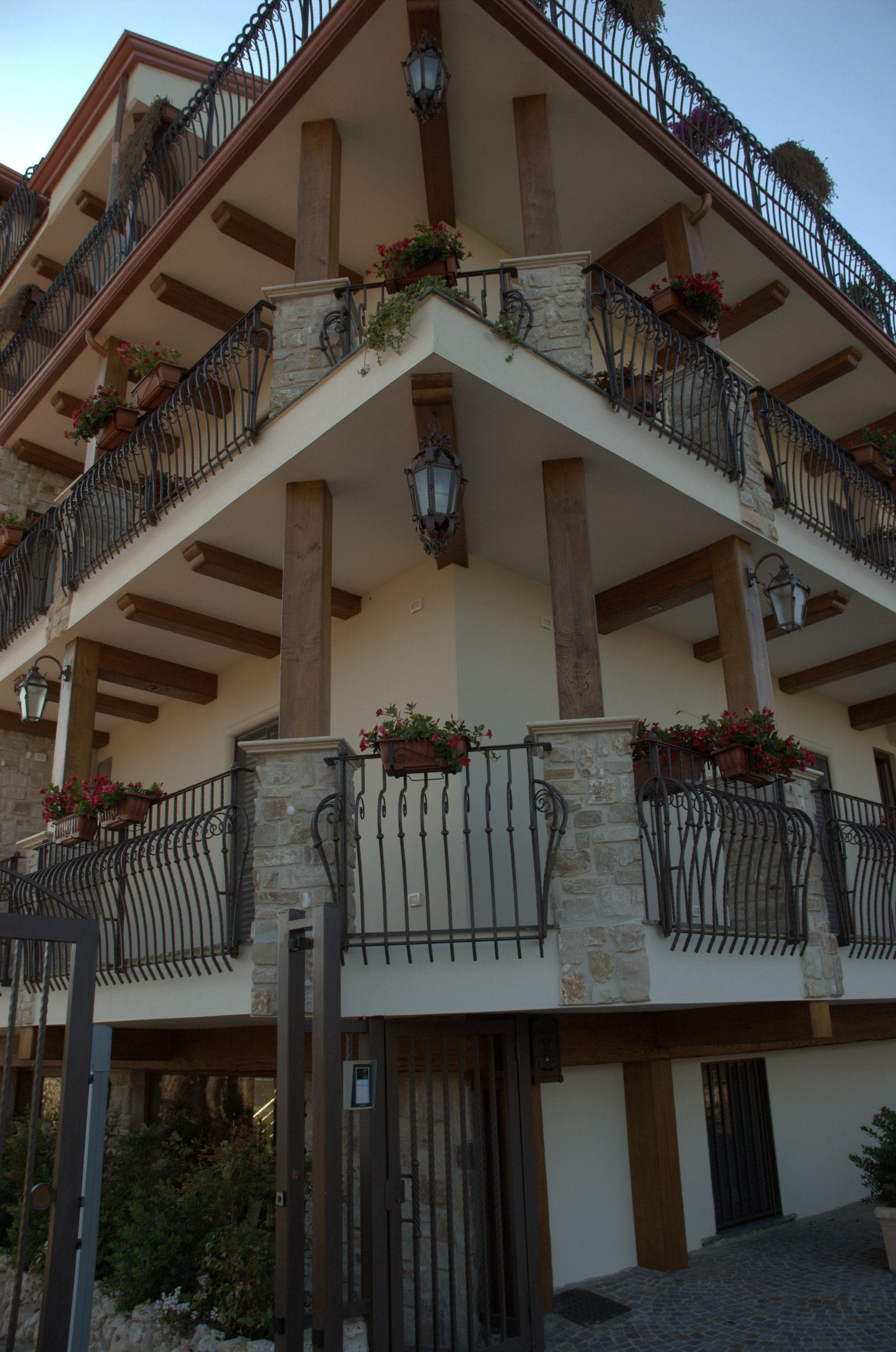 Un edificio de varios pisos con balcones decorados con jardineras, pilares de piedra y barandillas de hierro forjado.