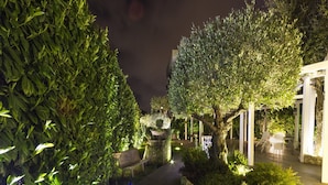 A nighttime garden pathway with a bench, a pergola, and a table with chairs. - Hotel Villa Clementina (Scafati)