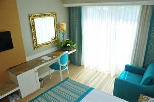 Habitación de hotel con escritorio, silla, cama y vistas al exterior.