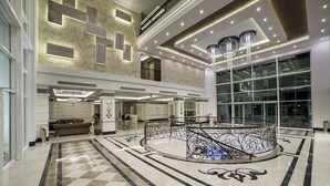 A spacious lobby with a checkered floor, a central decorative fountain, and a high ceiling with modern lighting fixtures. - Karmir Resort & Spa - Ultra All Inclusive (Kemer)