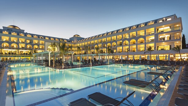 A hotel with a large swimming pool, multiple balconies, and a well-lit facade. - Karmir Resort & Spa - Ultra All Inclusive (Kemer)