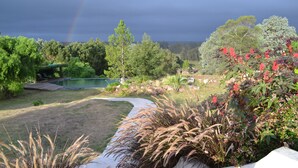 A landscaped garden with a pool, trees, and a rainbow in the background. - St Michel Wellness Hotel (Maldonado)