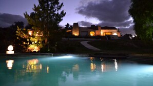 A nighttime view of a house with a swimming pool, surrounded by trees and illuminated by ambient lighting. - St Michel Wellness Hotel (Maldonado)
