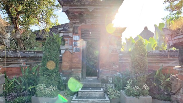A traditional gate with steps leading up to it, surrounded by potted plants and greenery. - Uma Dewi Guest House (Ubud)