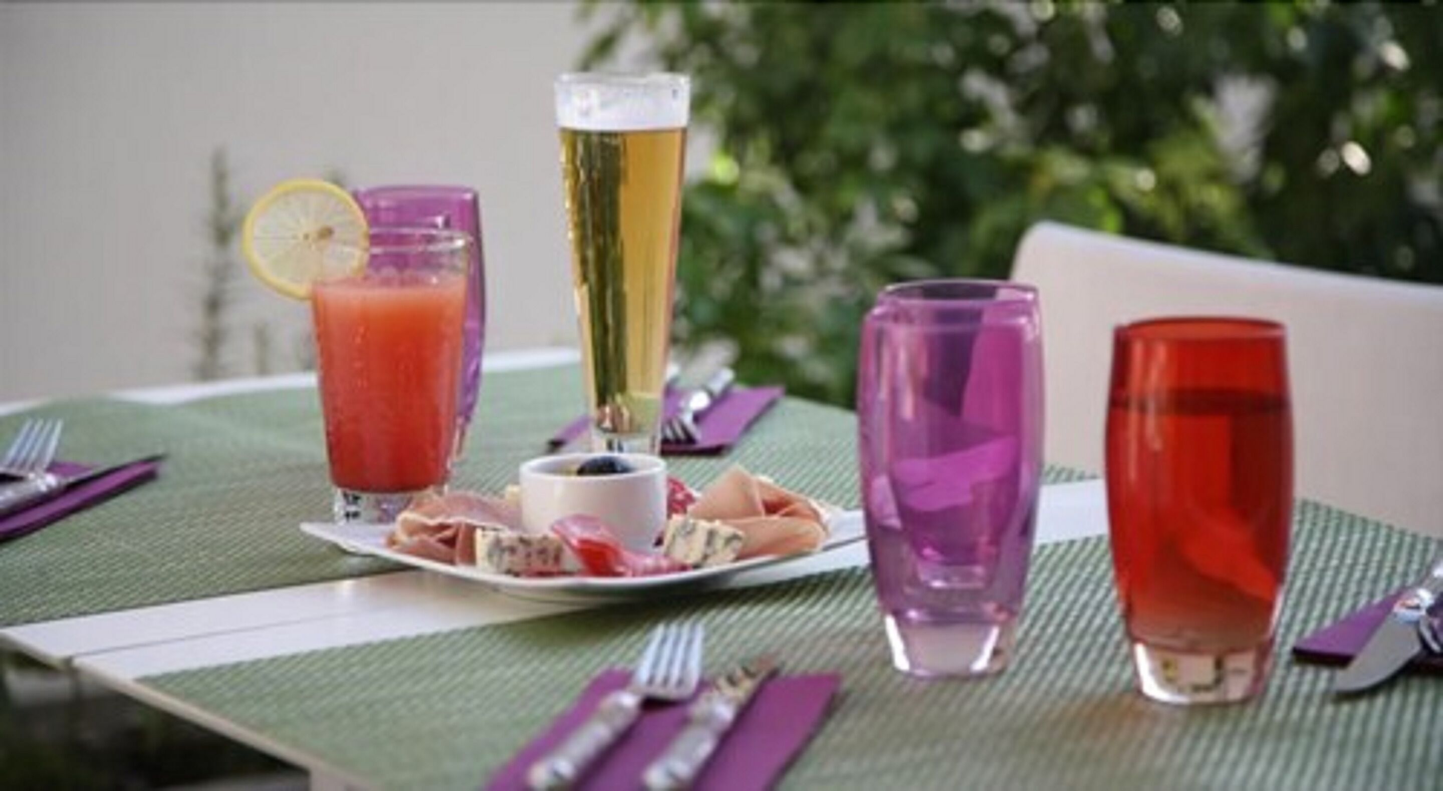 A table set with various drinks, a plate of food, and cutlery.