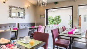 A hotel dining area with tables set for breakfast, including pastries and juice. - Le Figuier (Ivry-sur-Seine)
