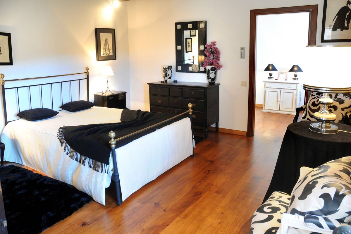 Une chambre à coucher comprenant un lit, une commode, une table de chevet et une petite table avec une lampe.