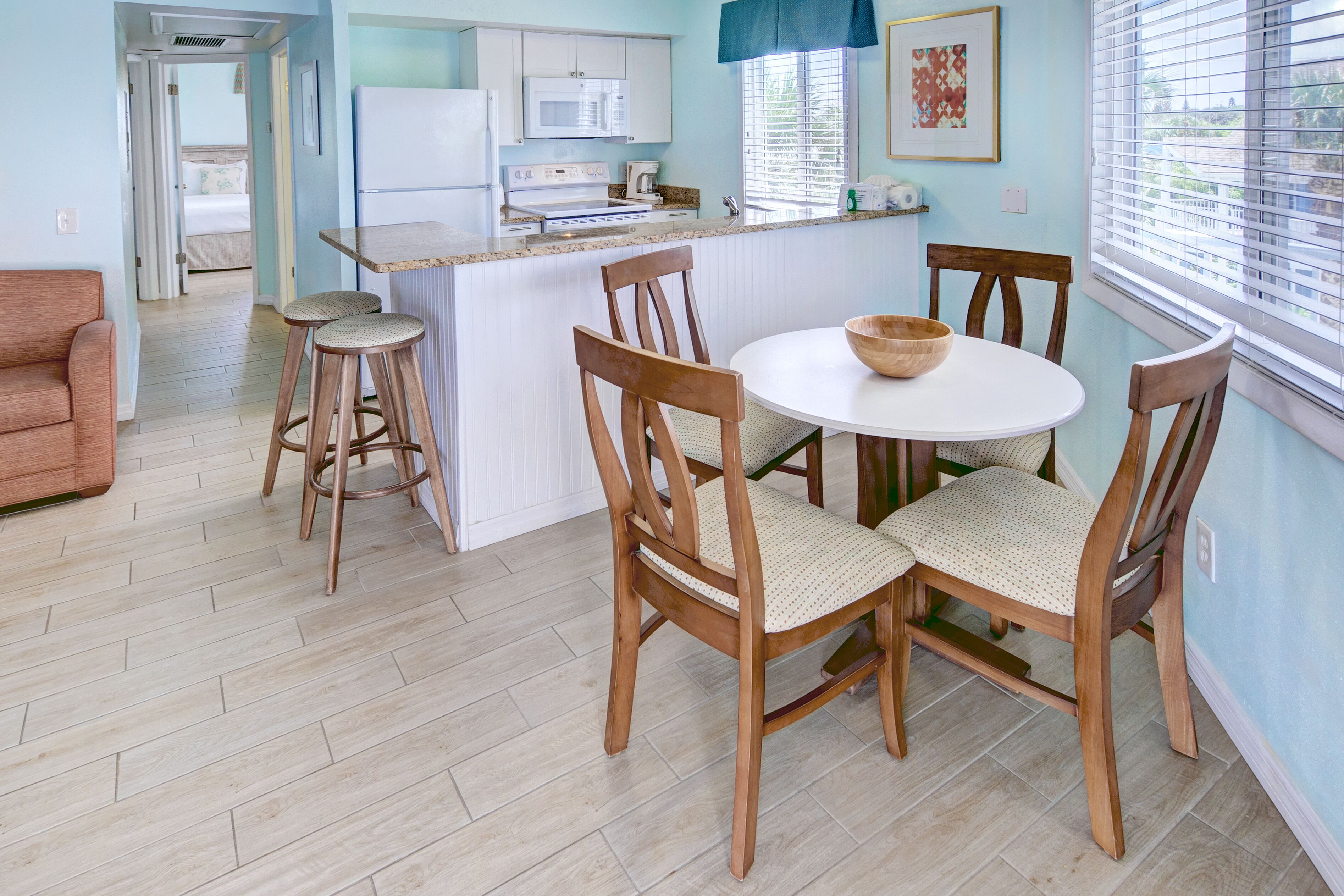 Una cocina moderna con una isla central, sillas de madera y una mesa de comedor.