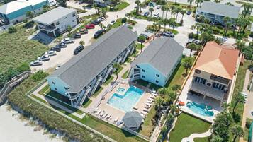 Una vista aerea di una zona residenziale con due grandi case, una piscina e una spiaggia.