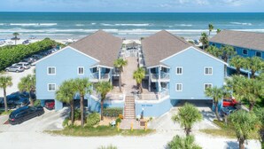 A beachfront hotel with two-story buildings, a central staircase, and a parking area.