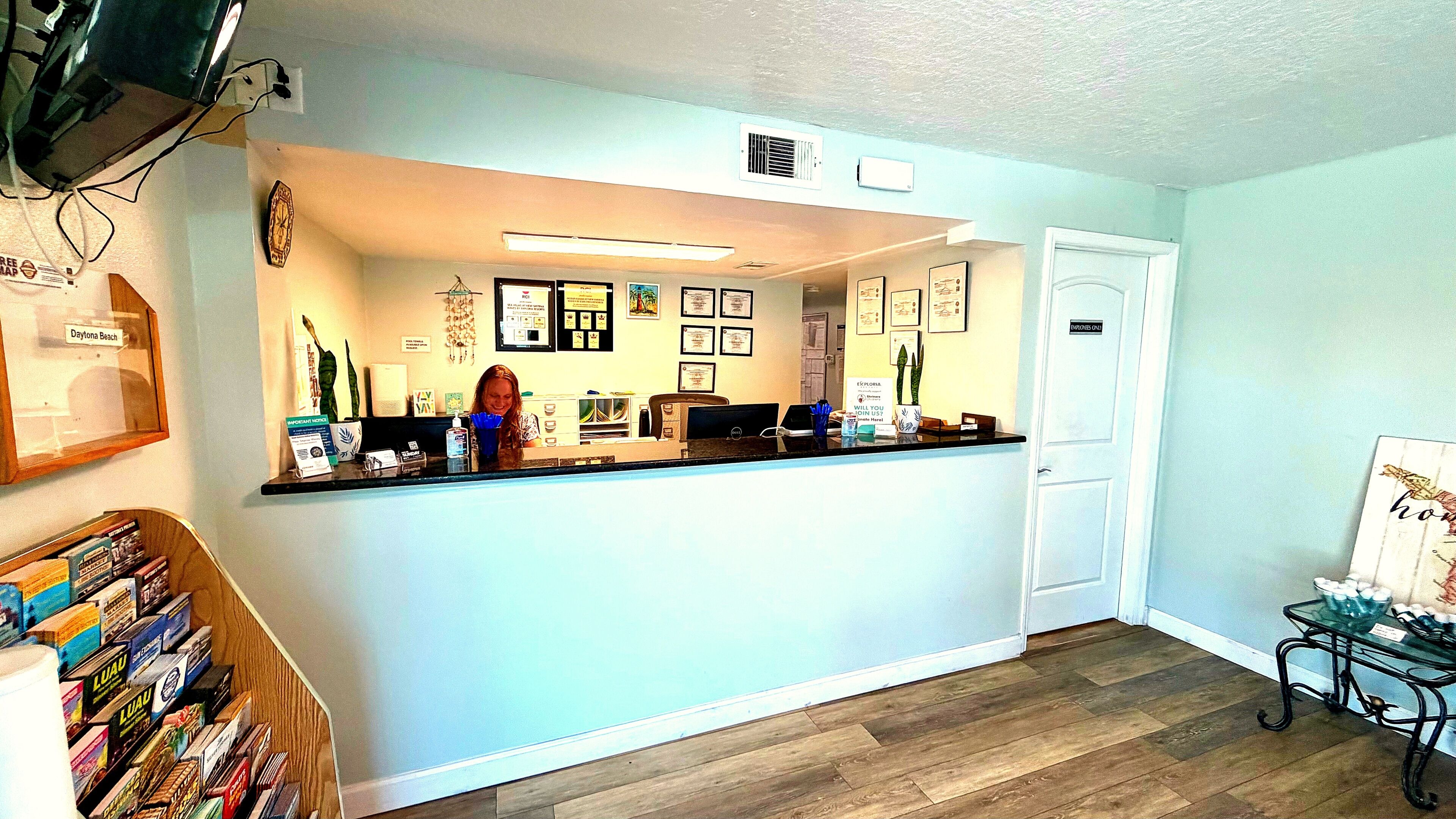 A reception area with a counter, framed certificates, a door labeled 'EMPLOYEES ONLY,' and a small table with a bowl of items.