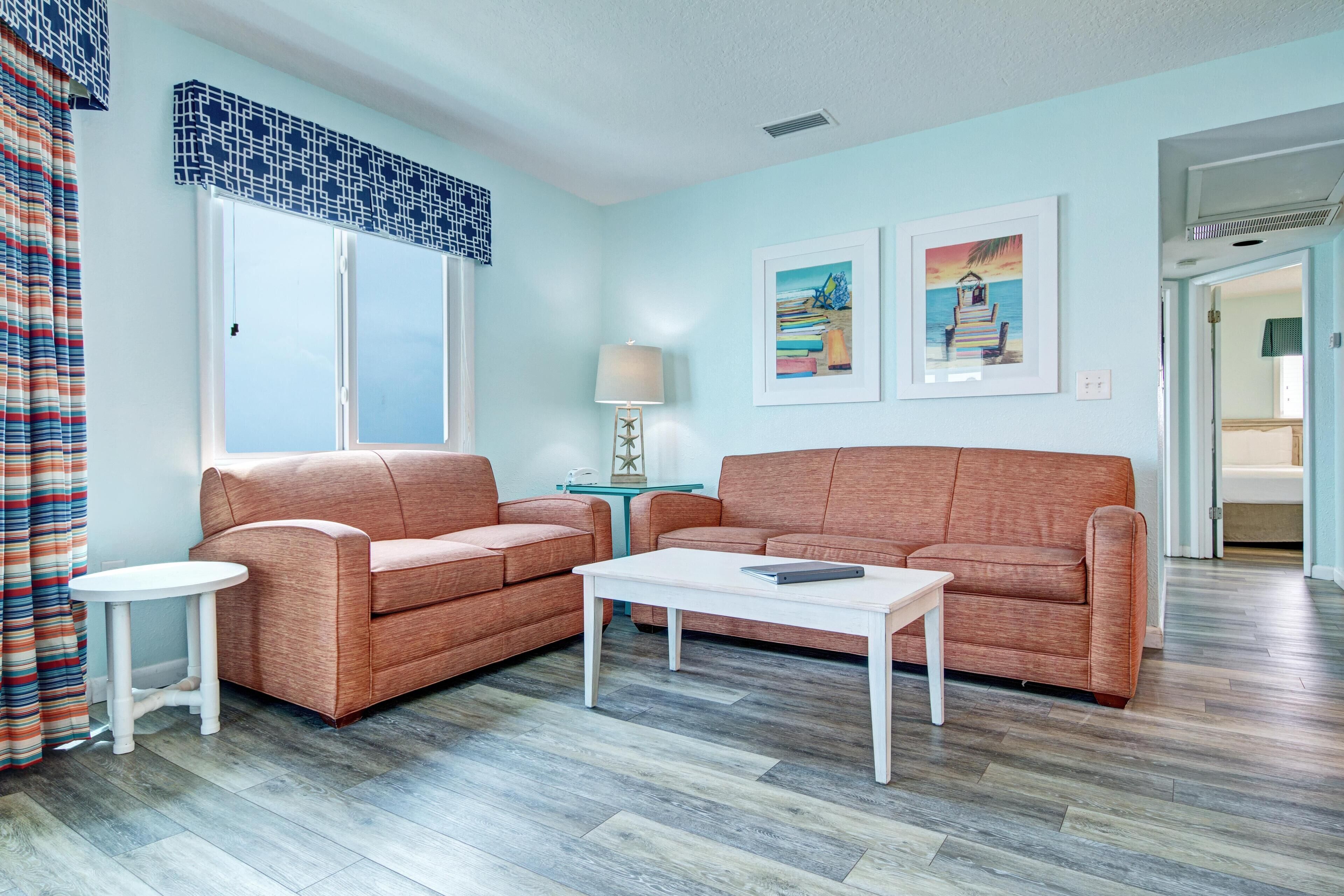 A living room with two sofas, a coffee table, a lamp, and two framed pictures on the wall.
