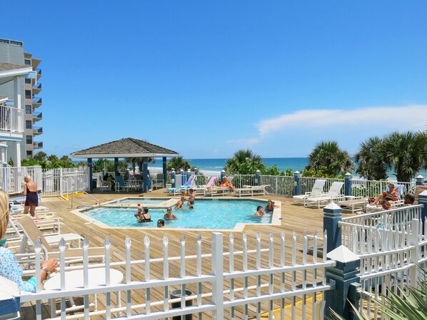 A pool area with a wooden deck, lounge chairs, and a small pavilion. - New Smyrna MOD Collection by Sonesta (New Smyrna Beach)