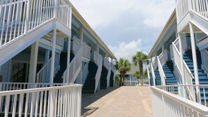 A corridor with a central pathway flanked by two-story buildings with balconies and staircases.