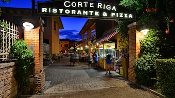 A brick building with a sign reading "Corte Riga Ristorante & Pizza".