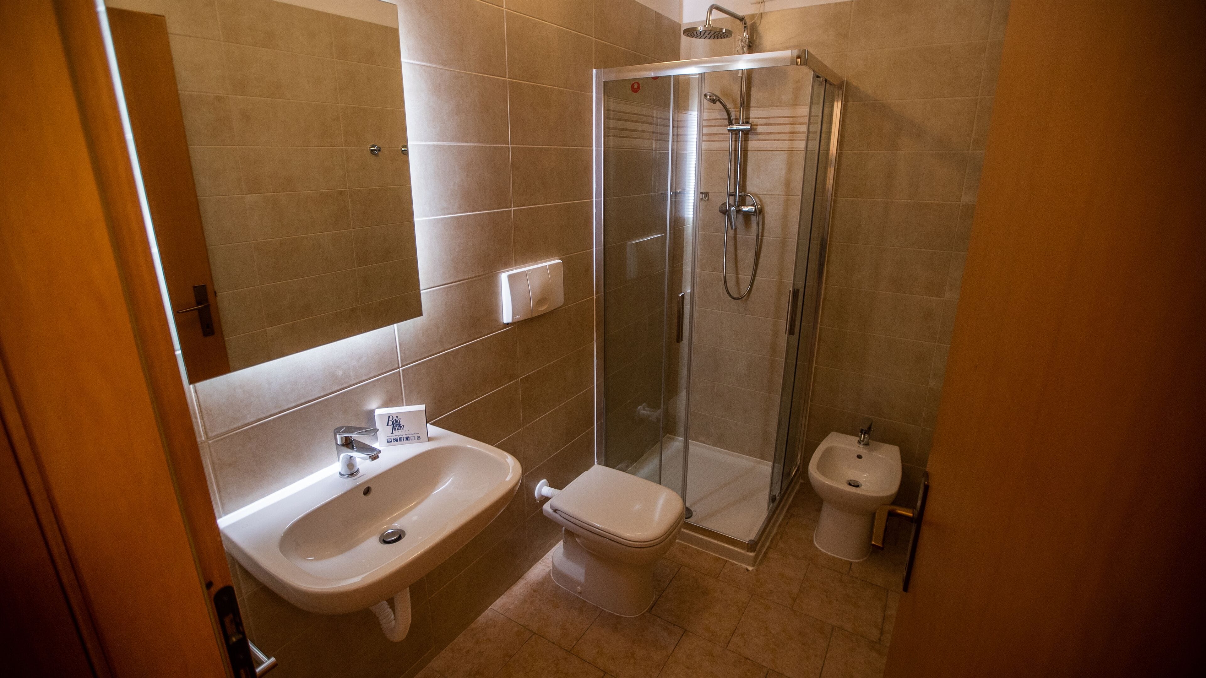 Un baño con lavamanos, inodoro, bidé y cabina de ducha con paredes de vidrio.