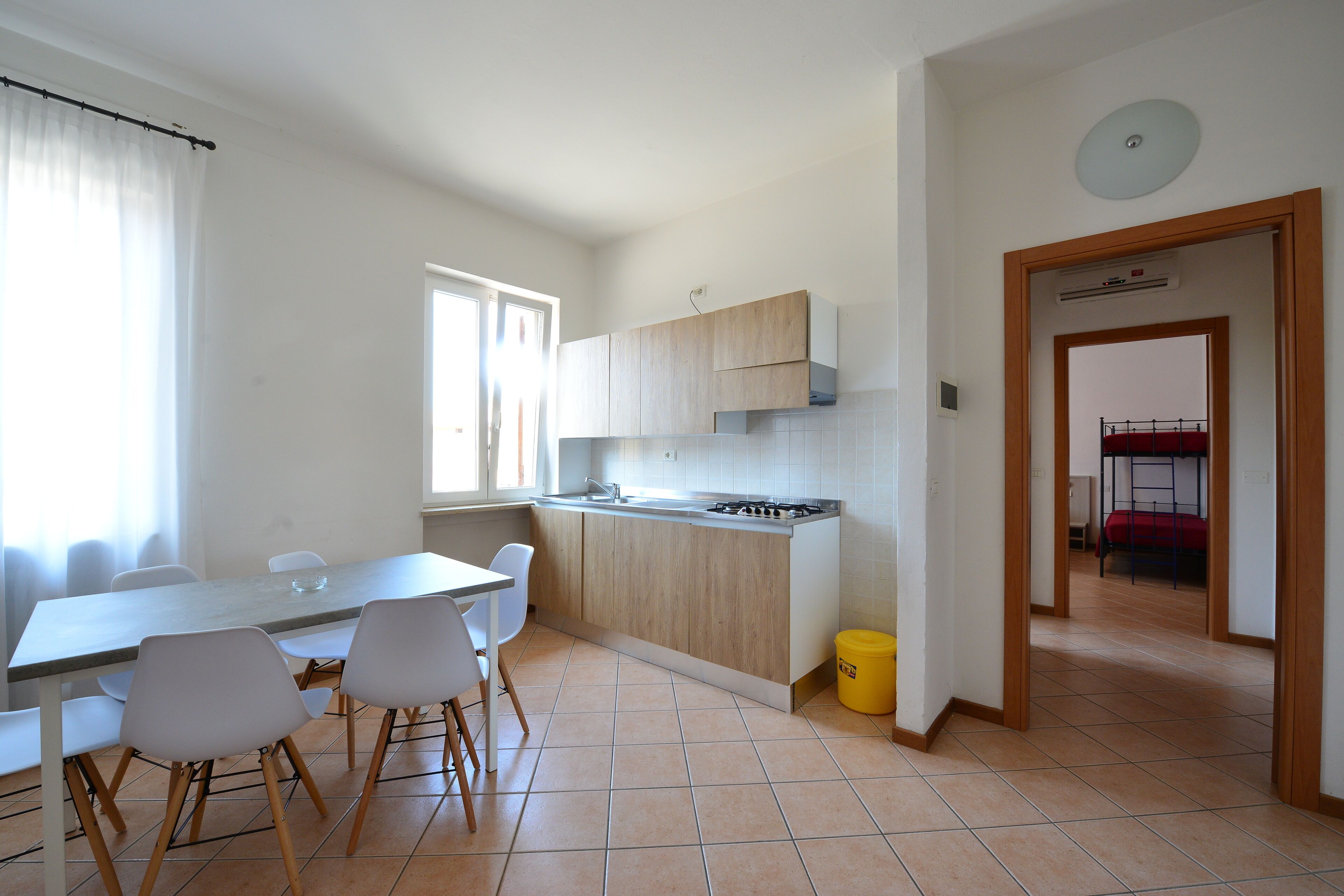 A modern kitchen with a dining area, white walls, and a visible window.