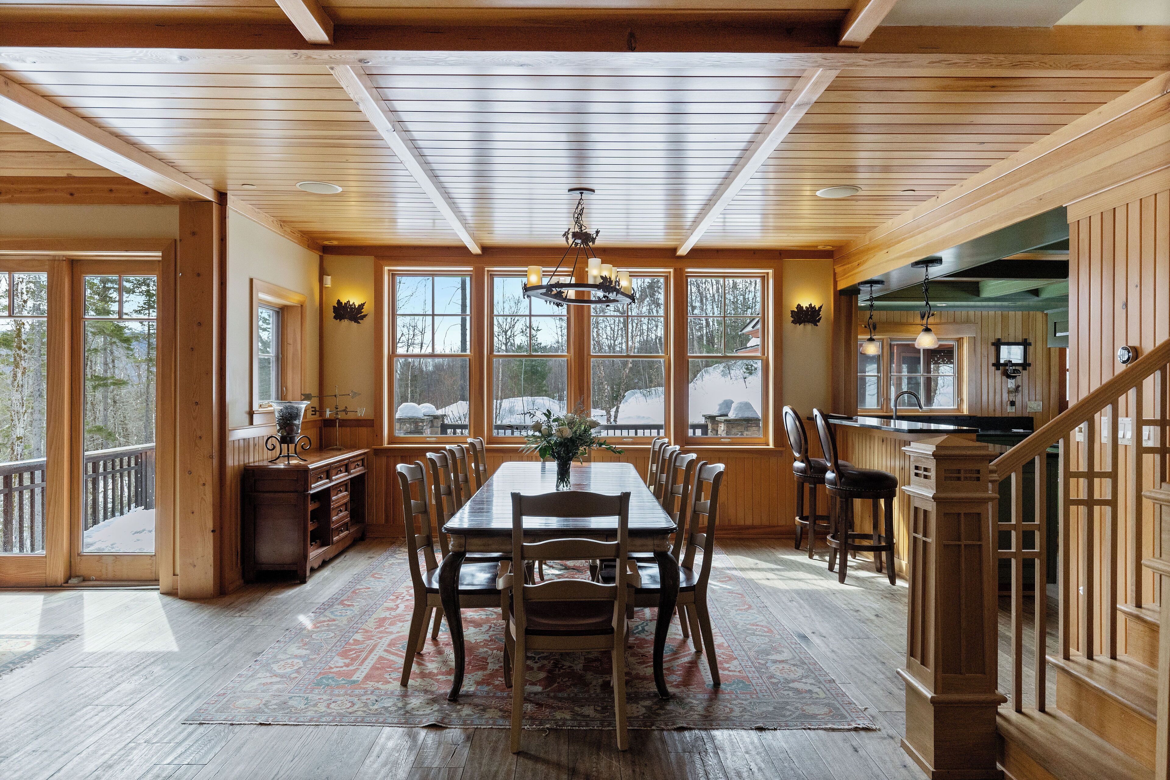 A spacious dining area with a large wooden table, multiple chairs, and a chandelier.