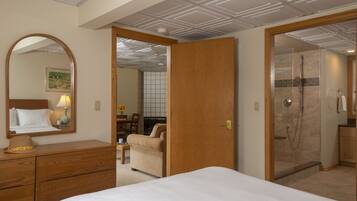 Habitación de hotel con cama, cómoda, espejo, ducha y vista al pasillo.
