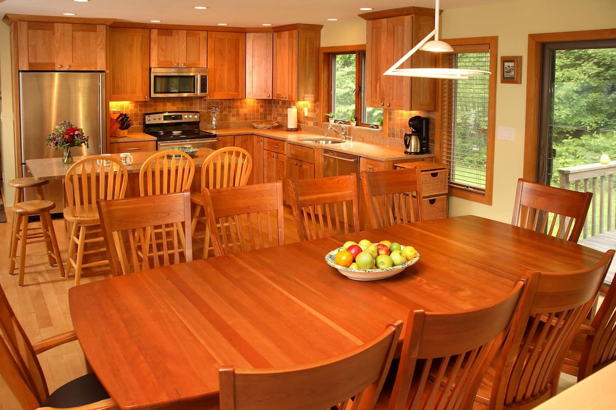 Una cocina moderna con armarios de madera, electrodomésticos de acero inoxidable y un comedor con mesa y sillas de madera.