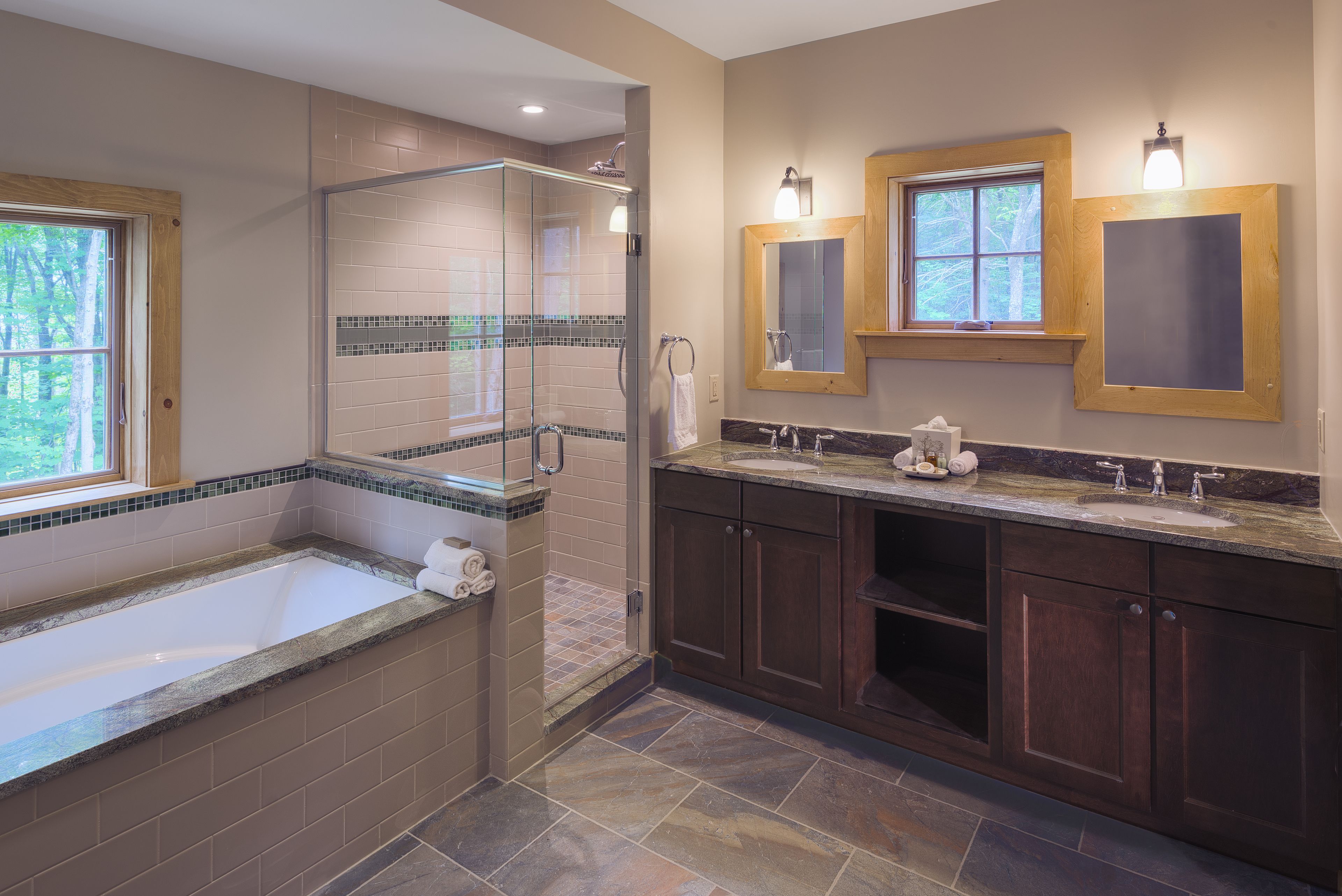 A modern bathroom with a glass-enclosed shower, a bathtub, and two sinks.