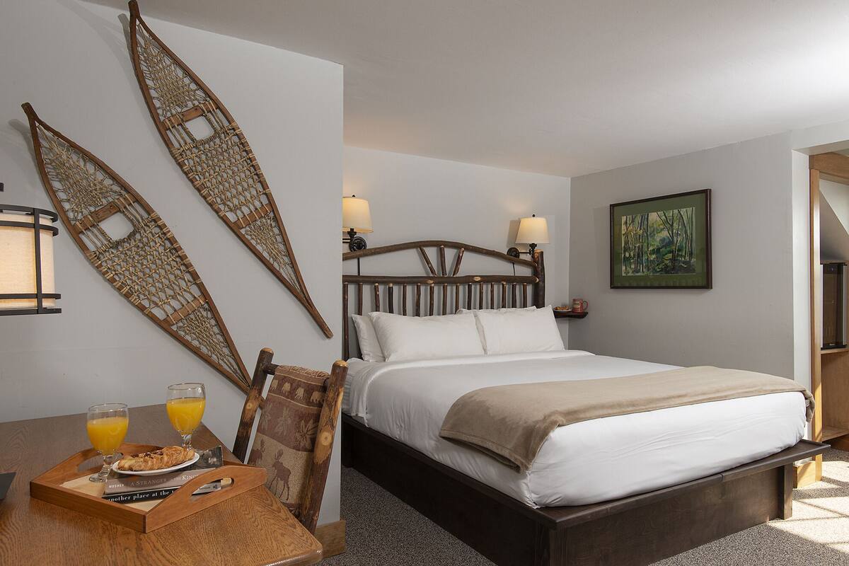 Un dormitorio ordenado con una cama de madera, una mesita de noche con una bandeja de desayuno y un adorno en la pared.