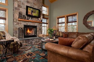 Una sala de estar acogedora con chimenea de piedra, sofá de cuero y alfombra estampada.