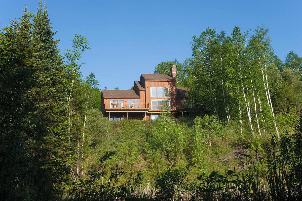 Una casa moderna con fachada de madera, ventanas grandes y un balcón.