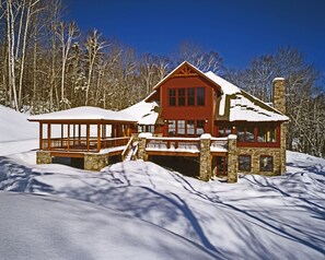 A two-story lodge with a stone foundation and a red exterior. It features a covered porch and a chimney. - The Mountain Top Inn & Resort (Chittenden)