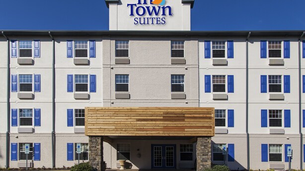 Un hotel de varios pisos con un letrero llamativo que dice "In Town Suites".