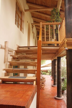 Una escalera de madera con barandilla lleva a un balcón.