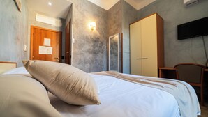 A hotel room with a bed, a wardrobe, a television, and a door with papers on it. - Hotel Angelica (Florence)