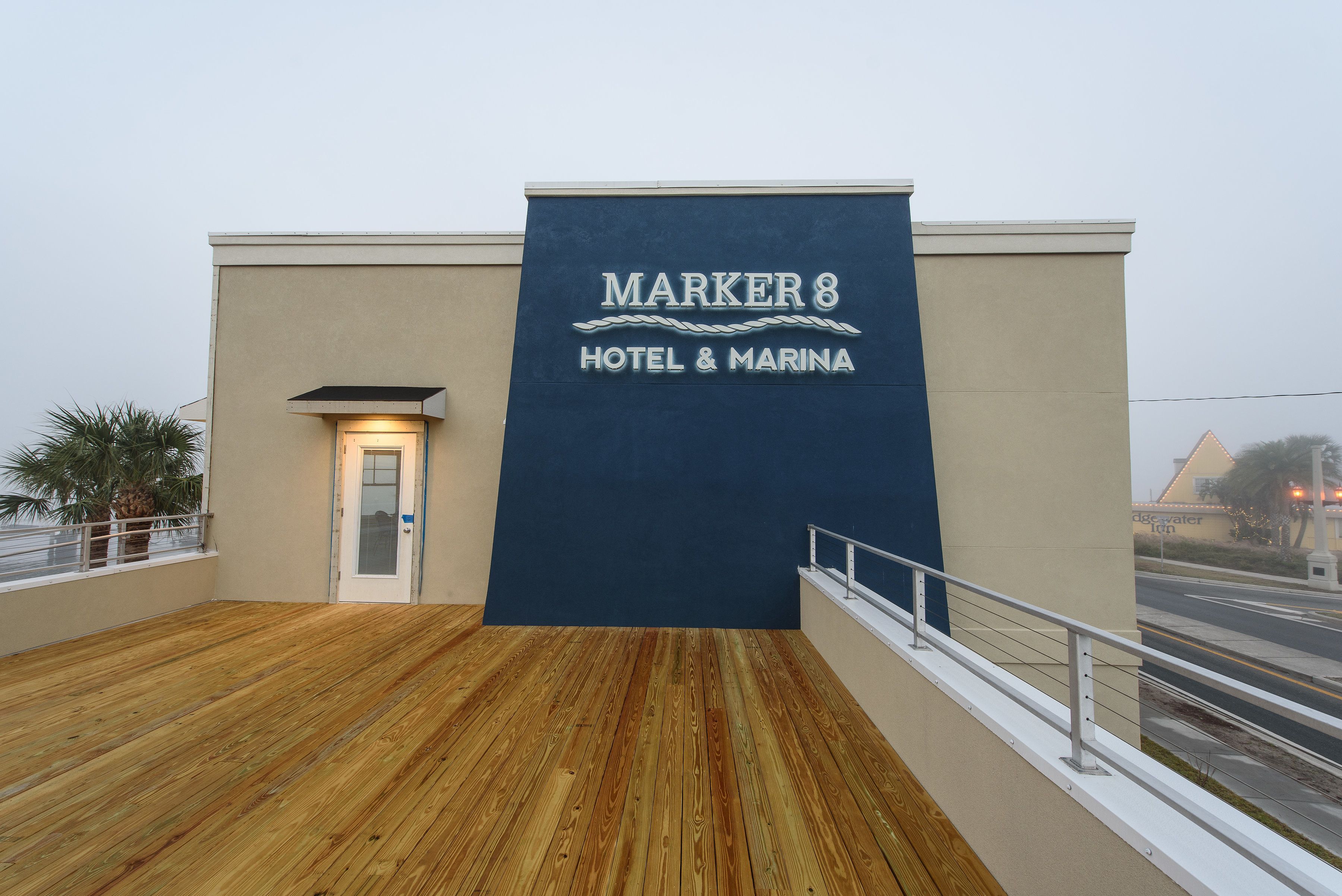 A hotel sign reading "MARKER 8 HOTEL & MARINA" with a wooden deck and a view of the street.