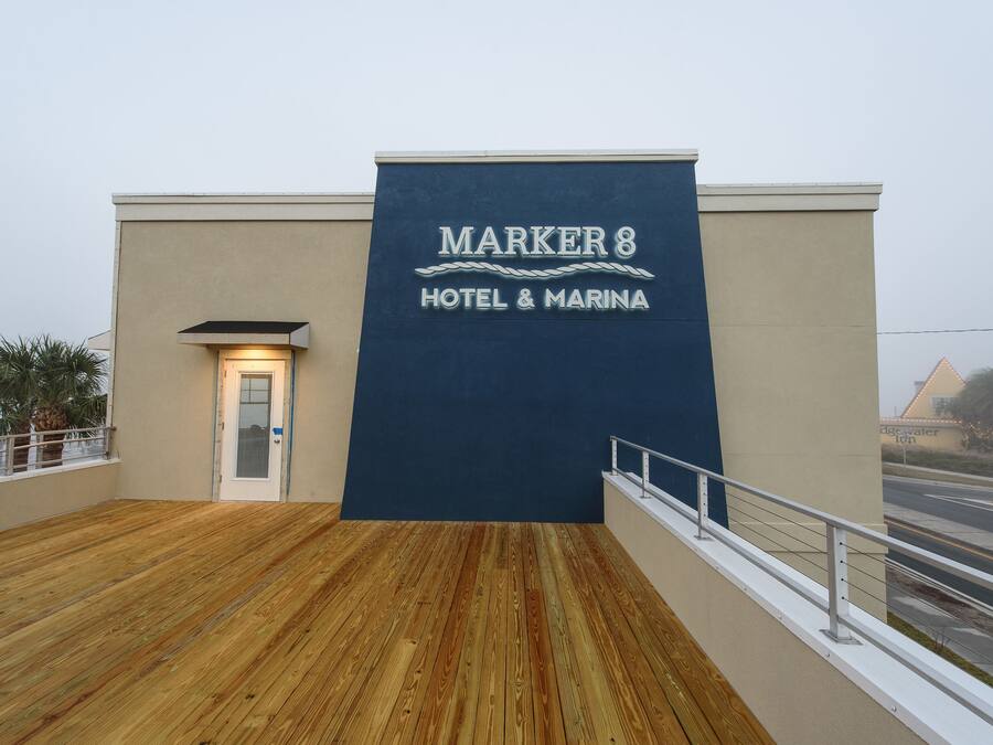 A hotel sign reading "MARKER 8 HOTEL & MARINA" with a wooden deck and a view of the street.