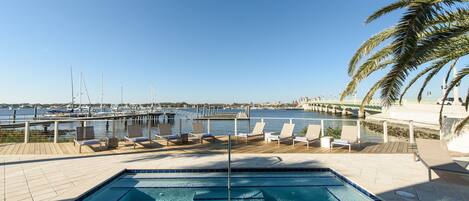A pool area with lounge chairs and a view of the marina.