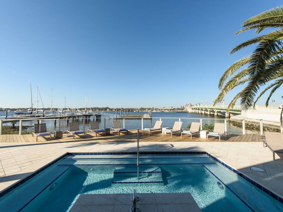 A pool area with lounge chairs and a view of the marina.