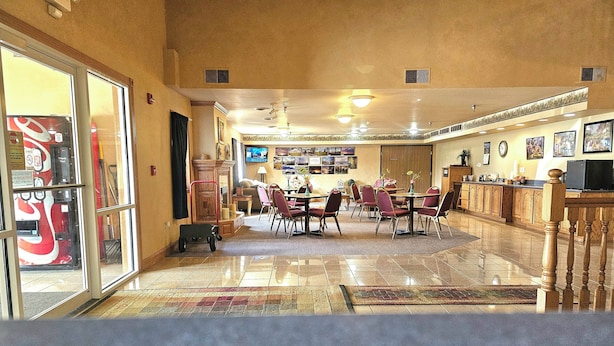 A hotel lobby with a dining area, a reception desk, and a television screen. - Park View Inn & Suites and Conference Center (West Bend)
