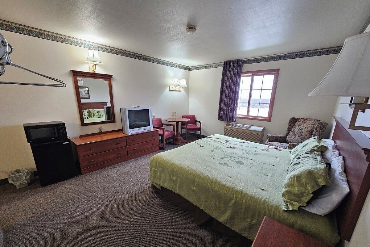 A hotel room with a bed, a TV, a desk, a chair, and a window.