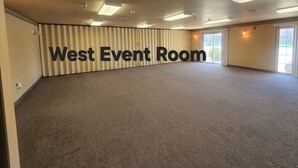 A large, empty room with a carpeted floor, ceiling lights, and a sign reading 'West Event Room.' - Park View Inn & Suites and Conference Center (West Bend)