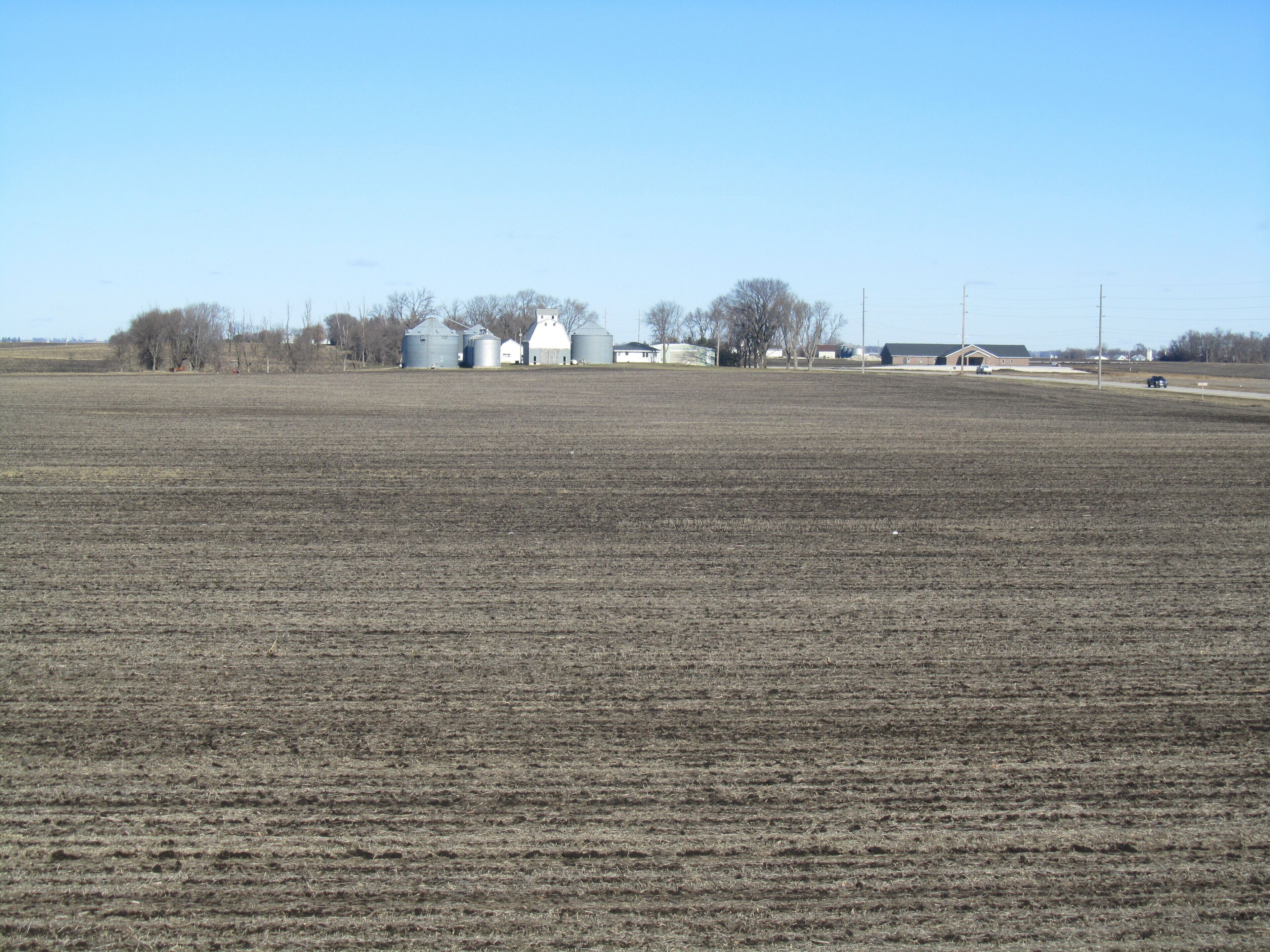 A vast, open field with a few buildings in the distance.