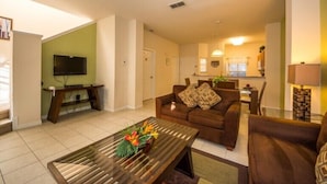A living room with a sofa, coffee table, and a television. - Encantada Resort by Home 2U (Kissimmee)