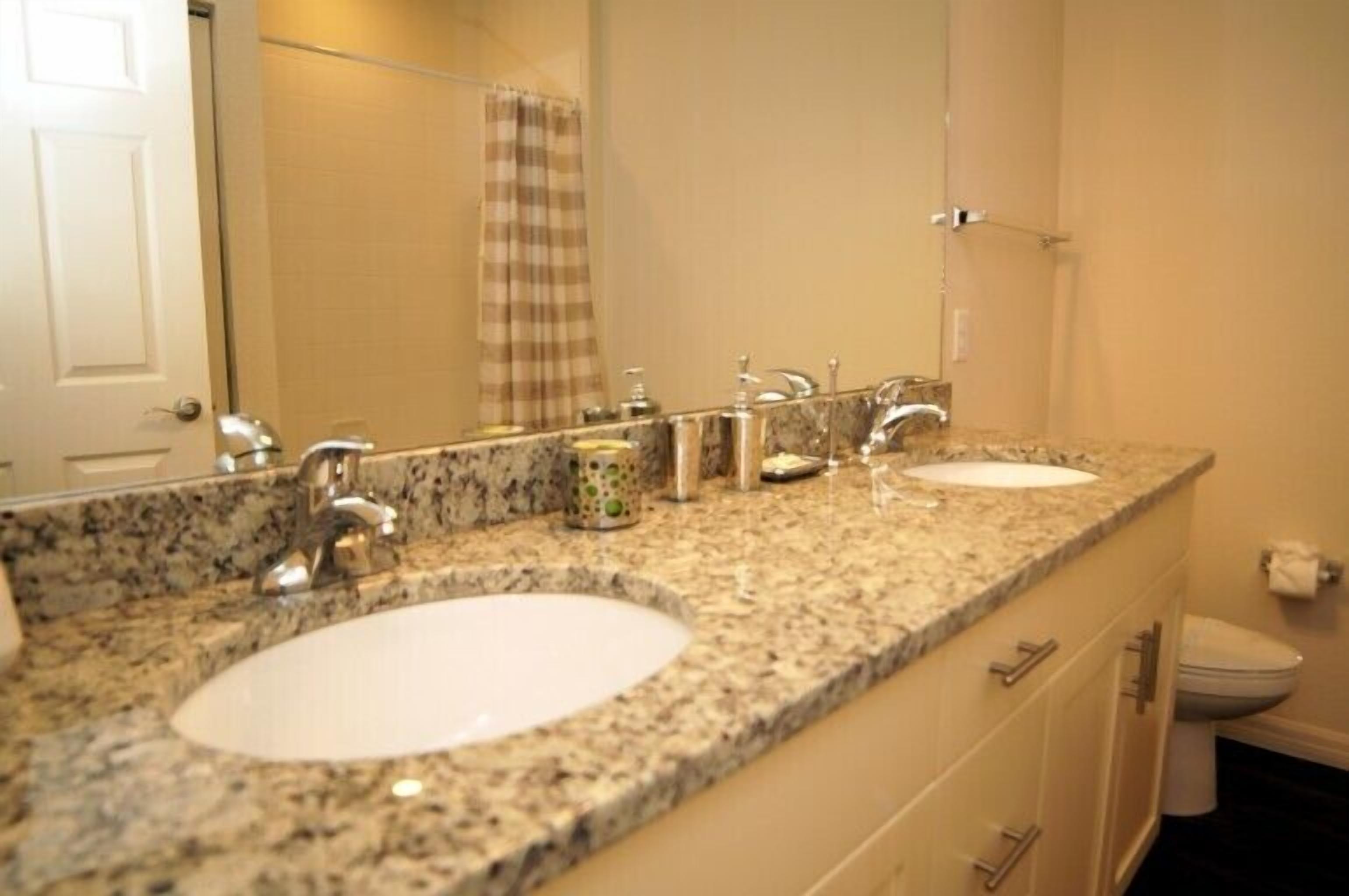 A bathroom with two sinks, a large mirror, and a toilet.