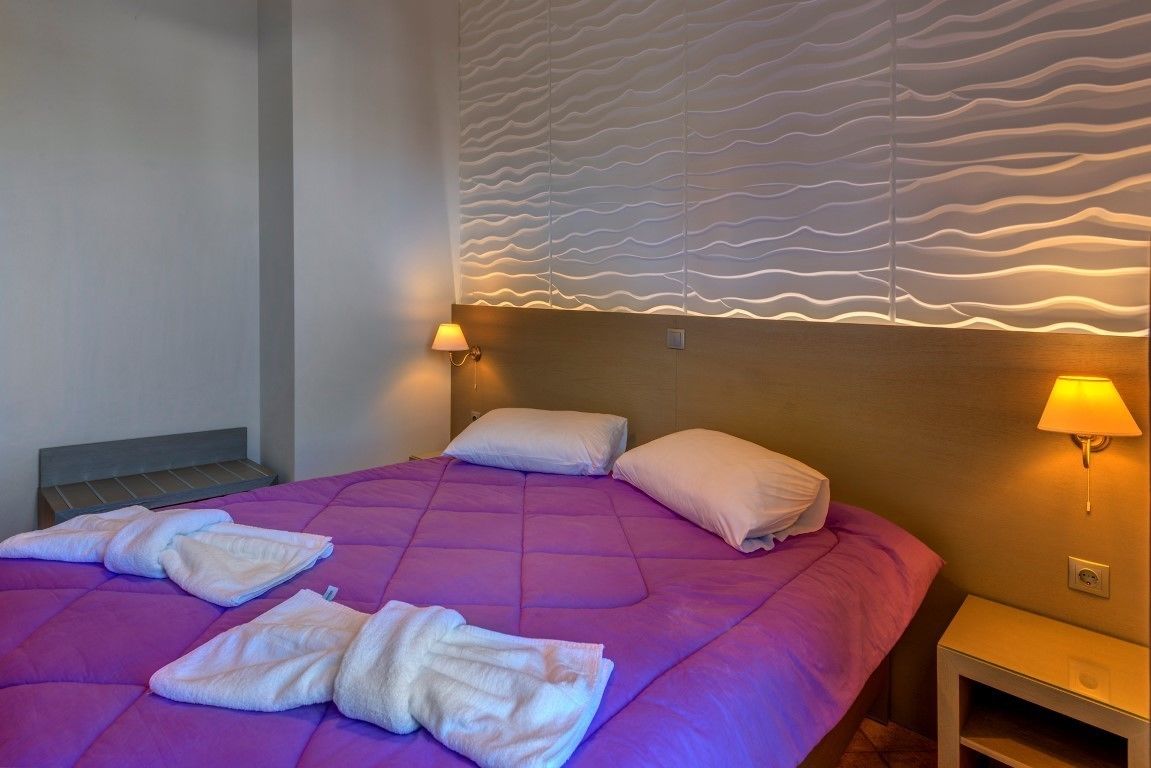 A hotel room with a large bed, two bedside lamps, and a textured wall design.