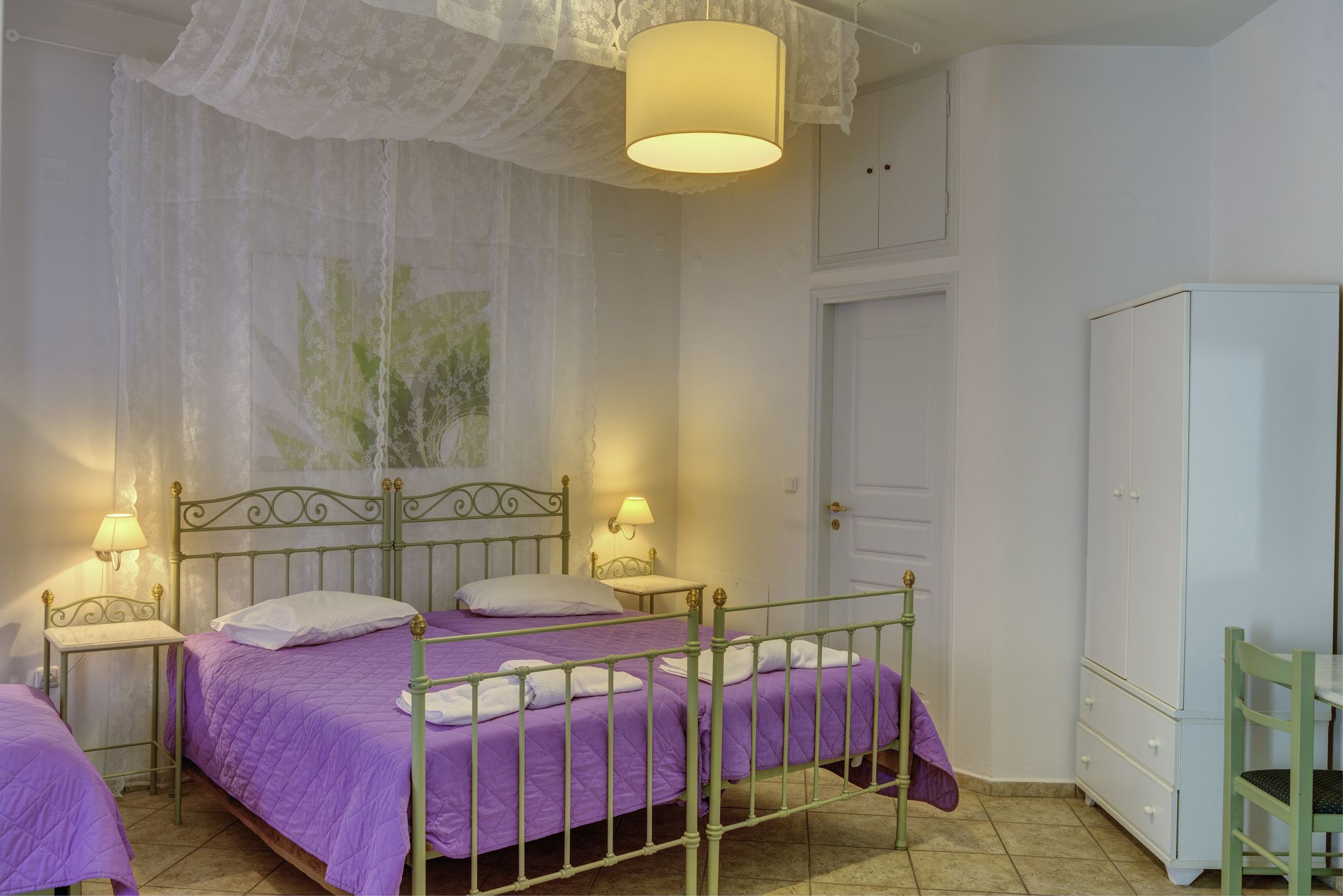 A bedroom with two beds, a wardrobe, and a chair.