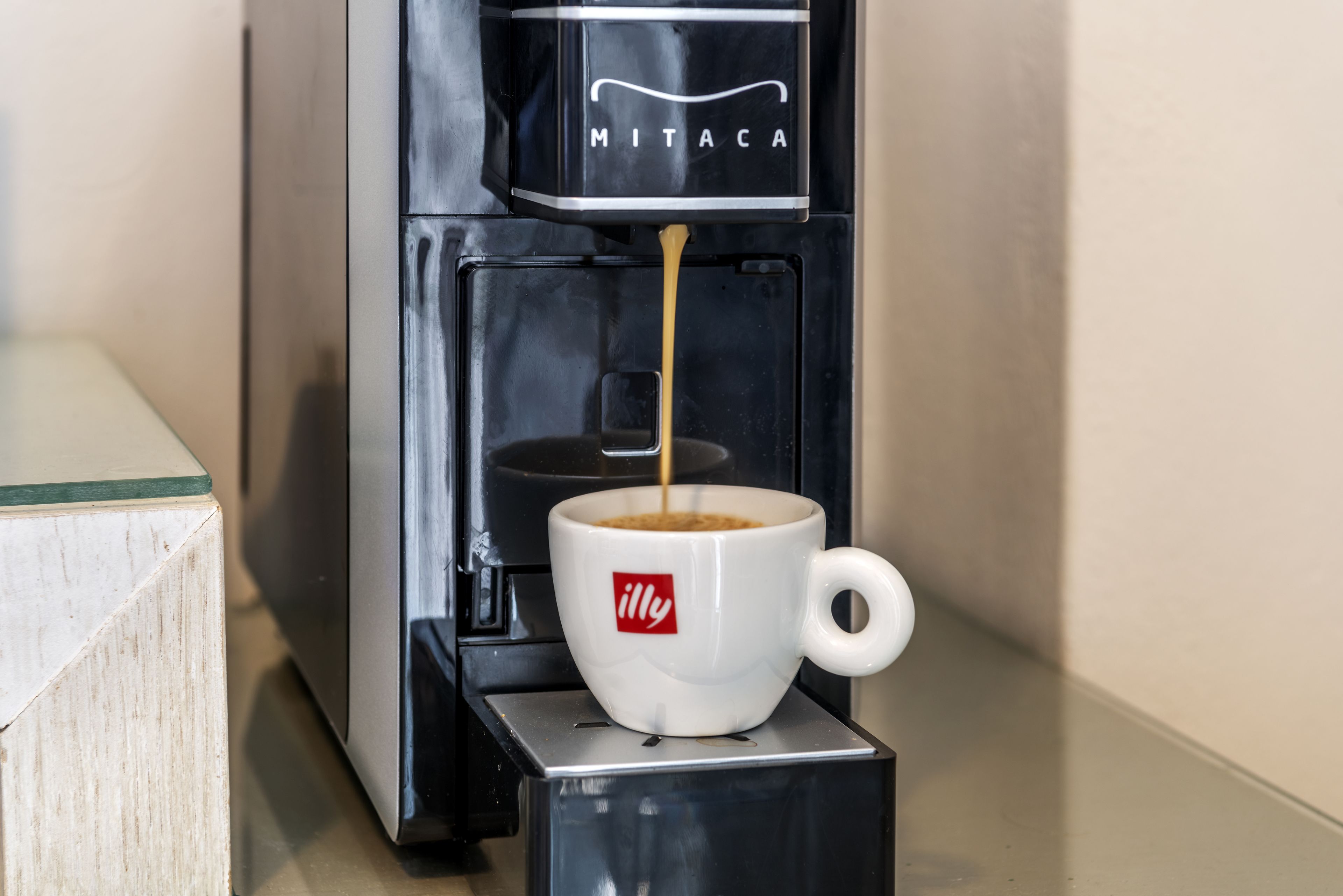A coffee machine dispensing coffee into a cup with a logo.