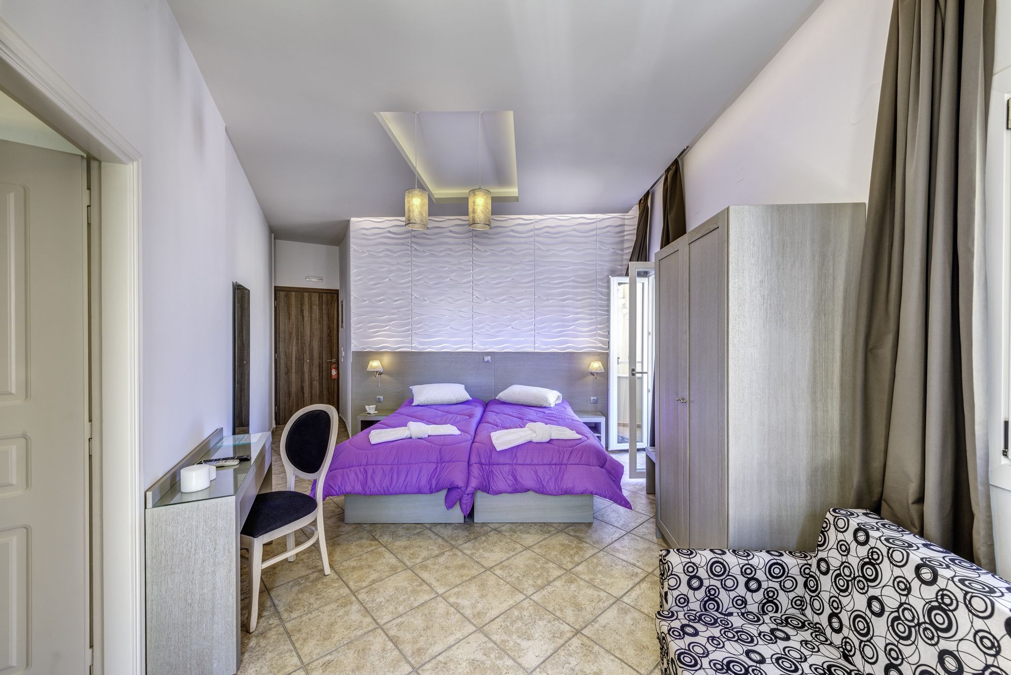 A hotel room with a bed, a desk, a chair, and a sofa.